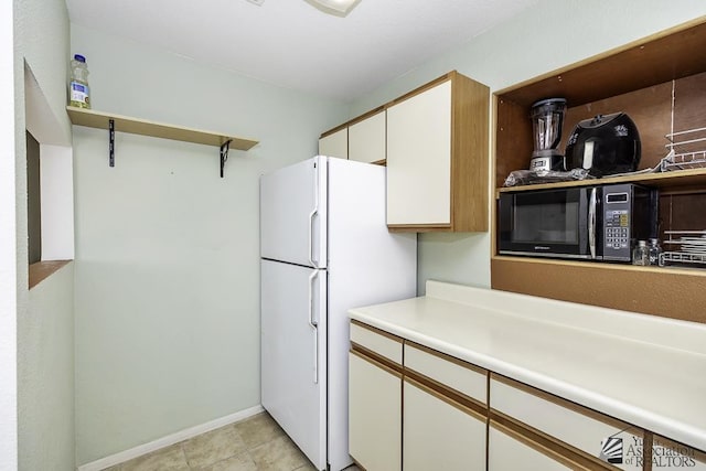 kitchen featuring white cabinetry and white fridge