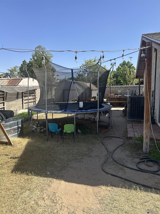 view of yard with central AC and a trampoline