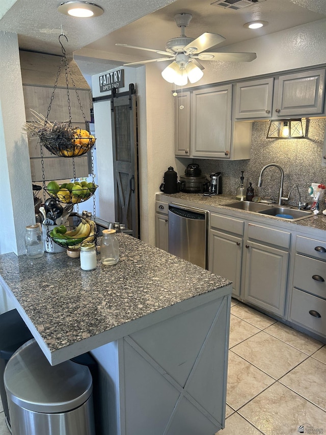 kitchen featuring dishwasher, sink, light tile patterned floors, gray cabinetry, and a barn door