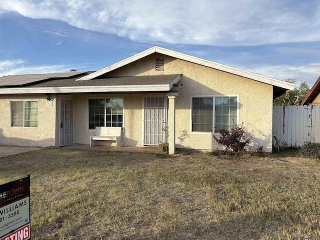 ranch-style house with a front yard and solar panels