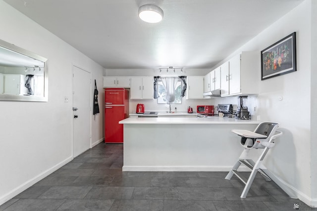 kitchen with range, a peninsula, light countertops, under cabinet range hood, and white cabinetry