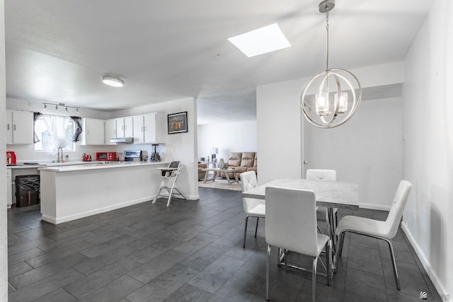 dining area featuring dark wood-type flooring, track lighting, a notable chandelier, and baseboards