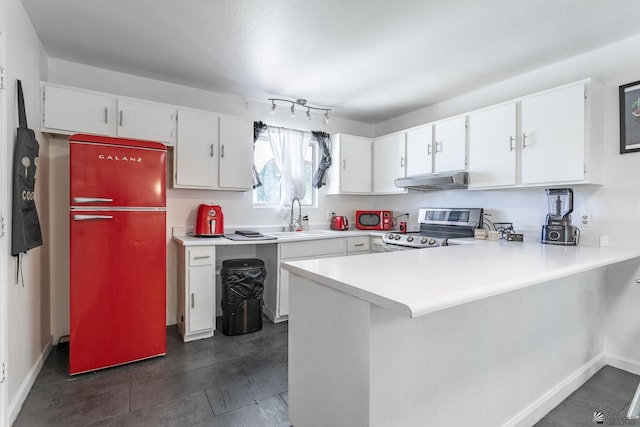 kitchen with under cabinet range hood, electric range, a sink, light countertops, and freestanding refrigerator