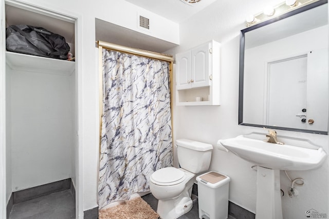 bathroom featuring toilet, a shower with shower curtain, a sink, and visible vents