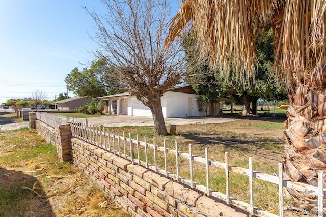 view of property exterior featuring a garage, driveway, and a fenced front yard