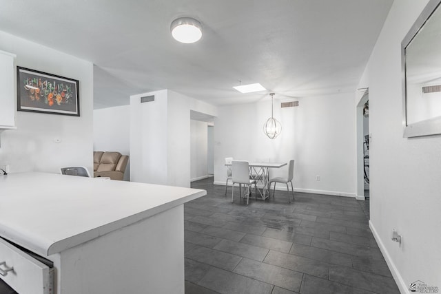 kitchen with a skylight, white cabinetry, visible vents, and light countertops