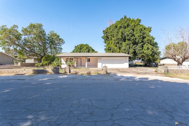 single story home featuring a garage, concrete driveway, and a fenced front yard