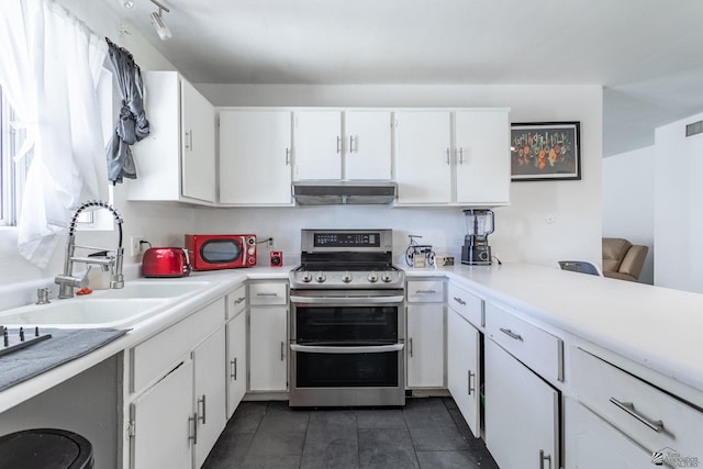 kitchen featuring range with two ovens, a sink, exhaust hood, white cabinets, and light countertops