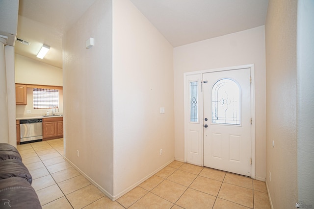 foyer entrance featuring light tile patterned flooring, lofted ceiling, and sink