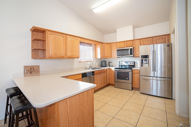 kitchen featuring kitchen peninsula, stainless steel appliances, vaulted ceiling, sink, and light tile patterned flooring