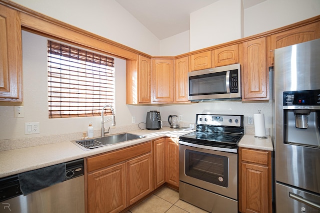 kitchen with lofted ceiling, light tile patterned floors, sink, and appliances with stainless steel finishes