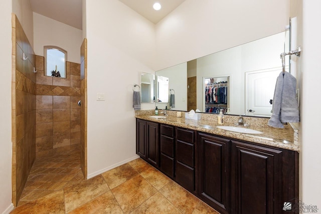 bathroom with tiled shower, vanity, and lofted ceiling