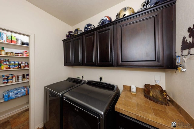 clothes washing area with cabinets and washer and clothes dryer