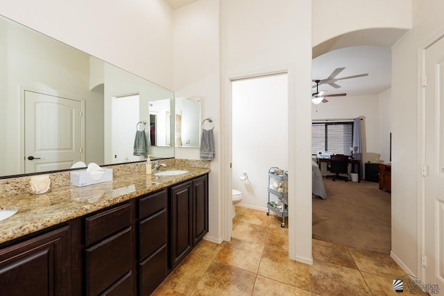 bathroom featuring tile patterned floors, toilet, vanity, a towering ceiling, and ceiling fan