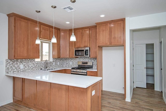 kitchen featuring sink, stainless steel appliances, dark wood-type flooring, kitchen peninsula, and pendant lighting