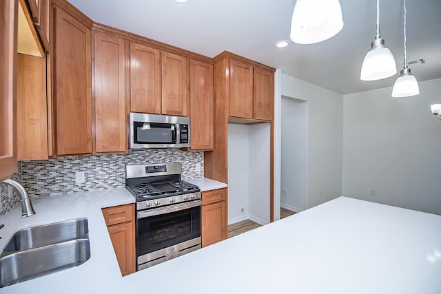 kitchen featuring backsplash, decorative light fixtures, sink, and stainless steel appliances