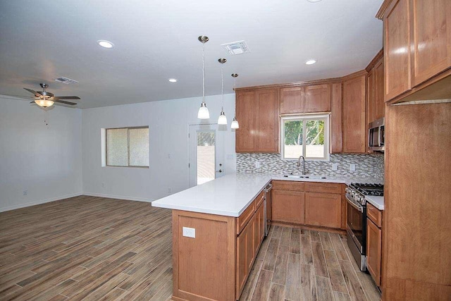 kitchen featuring kitchen peninsula, appliances with stainless steel finishes, ceiling fan, sink, and decorative light fixtures