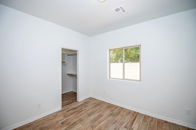 unfurnished bedroom with light hardwood / wood-style floors, a spacious closet, and a closet