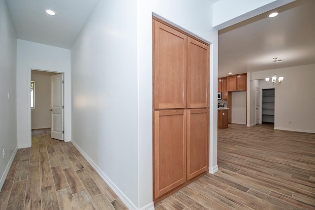 hallway featuring light hardwood / wood-style floors and an inviting chandelier