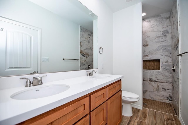 bathroom with vanity, toilet, and tiled shower