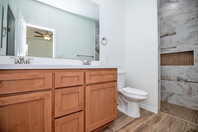 bathroom featuring vanity, ceiling fan, toilet, and tiled shower