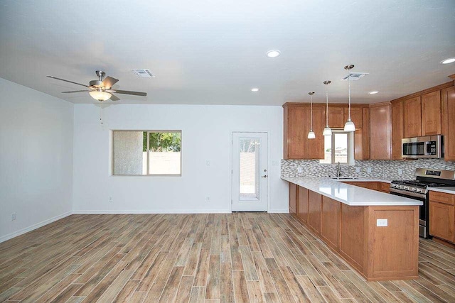 kitchen with sink, hanging light fixtures, stainless steel appliances, tasteful backsplash, and kitchen peninsula