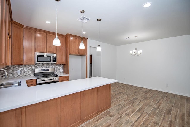 kitchen with pendant lighting, sink, kitchen peninsula, and stainless steel appliances