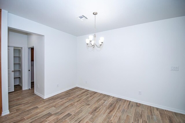 unfurnished room with a notable chandelier