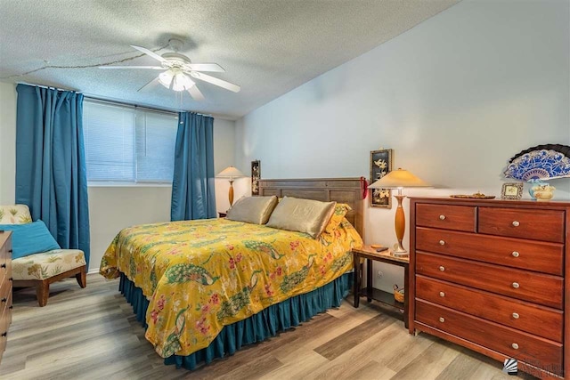 bedroom with ceiling fan, light hardwood / wood-style floors, and a textured ceiling