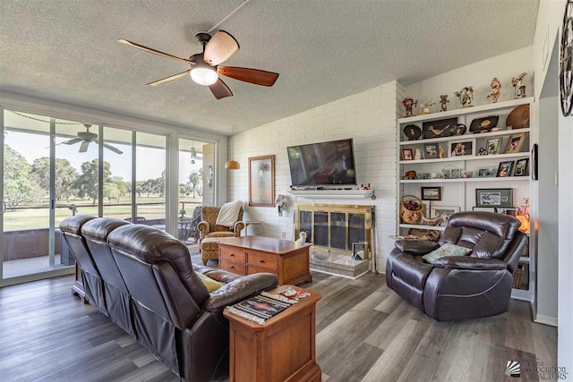 living room featuring a textured ceiling, ceiling fan, wood-type flooring, and a fireplace