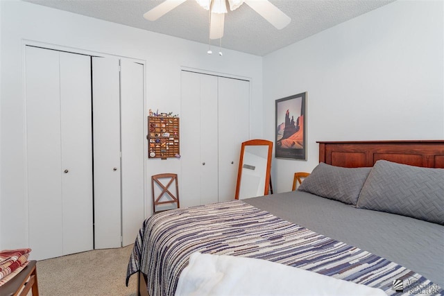 bedroom with ceiling fan, carpet floors, a textured ceiling, and two closets