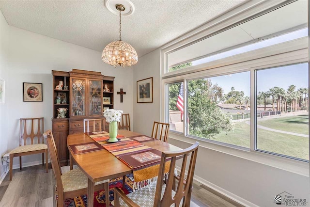 dining area with hardwood / wood-style flooring, a chandelier, and a textured ceiling