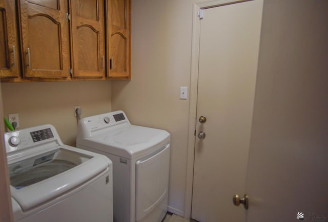 clothes washing area featuring washer and clothes dryer and cabinet space