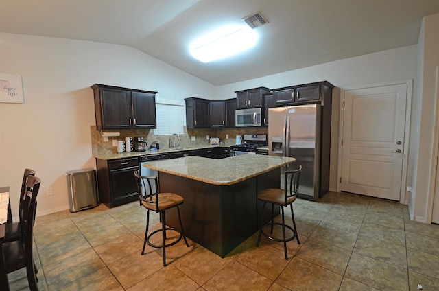 kitchen featuring a kitchen bar, visible vents, a sink, backsplash, and stainless steel appliances