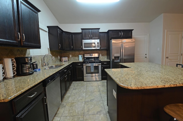 kitchen with a sink, stainless steel appliances, light stone counters, and tasteful backsplash