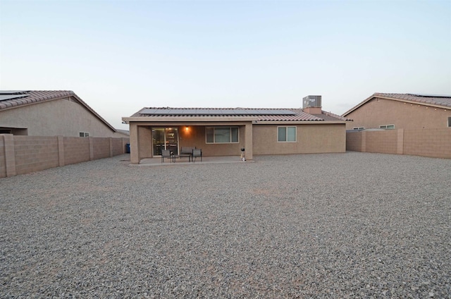 back of house featuring stucco siding, a patio, solar panels, and a fenced backyard