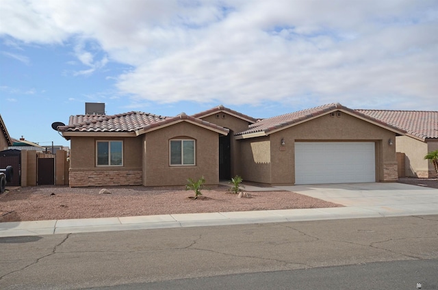 mediterranean / spanish home featuring fence, concrete driveway, stucco siding, stone siding, and an attached garage