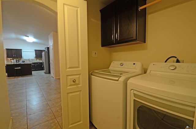 laundry area featuring light tile patterned floors, cabinet space, independent washer and dryer, and arched walkways