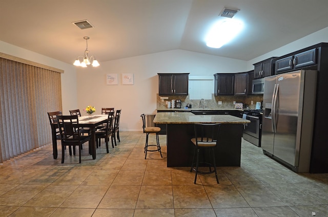 kitchen with stainless steel appliances, lofted ceiling, visible vents, and a center island