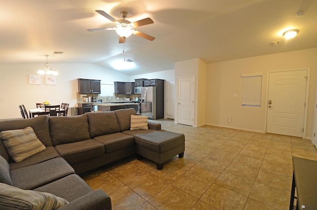 living area with light tile patterned floors, ceiling fan with notable chandelier, baseboards, and lofted ceiling