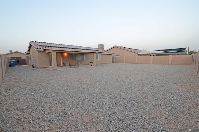 rear view of house with a patio, solar panels, a fenced backyard, stucco siding, and a tiled roof