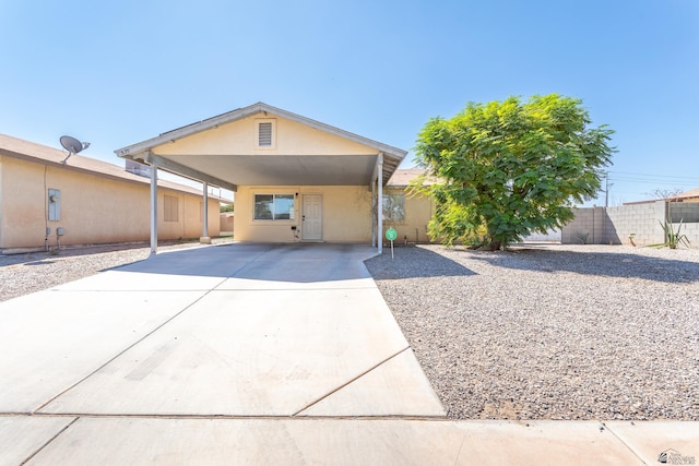 view of front facade with concrete driveway, fence, and stucco siding