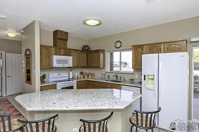 kitchen with a breakfast bar, white appliances, sink, a textured ceiling, and a kitchen island