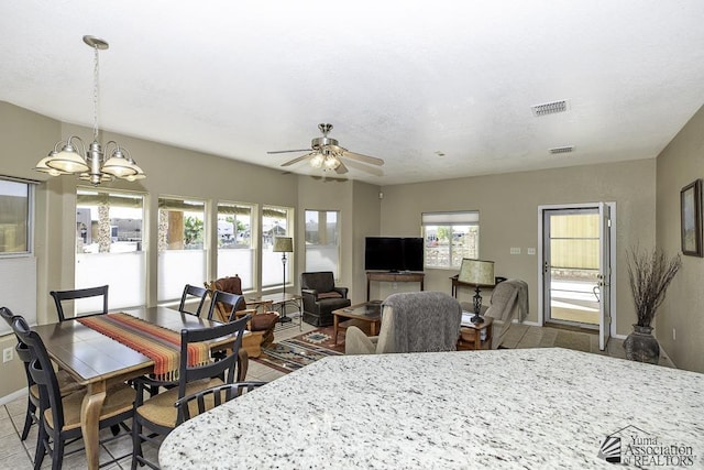 dining space featuring a wealth of natural light and ceiling fan with notable chandelier