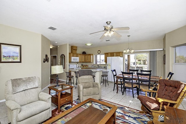 living room with ceiling fan with notable chandelier, a wealth of natural light, and light tile patterned flooring