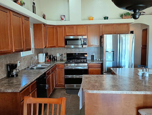 kitchen featuring dark tile patterned flooring, sink, appliances with stainless steel finishes, and tasteful backsplash