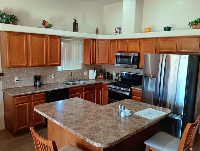 kitchen with black appliances, dark tile patterned flooring, sink, tasteful backsplash, and a breakfast bar area