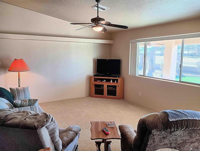 living room featuring carpet flooring, ceiling fan, and a textured ceiling