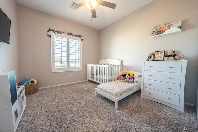 carpeted bedroom featuring a nursery area and ceiling fan