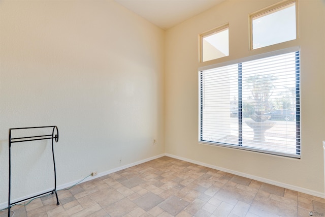 spare room featuring stone finish floor and baseboards